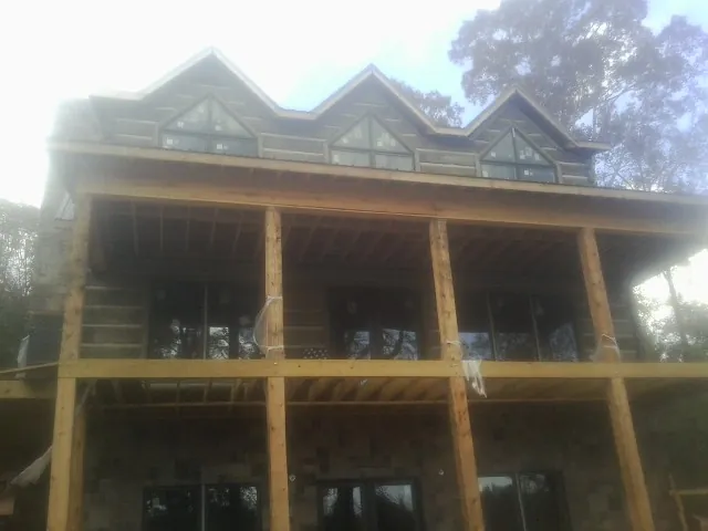 Dormers and porch framing on a large log home under construction — Roof Coating work by our crew in Fischer